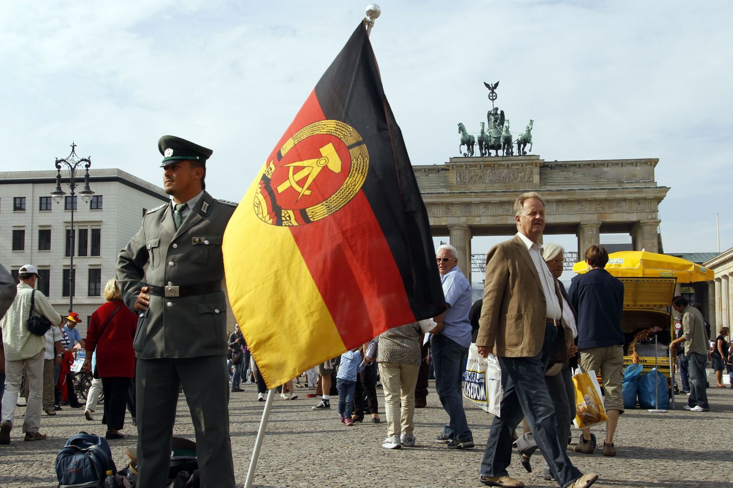 Saksa Demokraatliku Vabariigi lipuga poseeriv tänavaartist Brandenburgi väravate juures.
