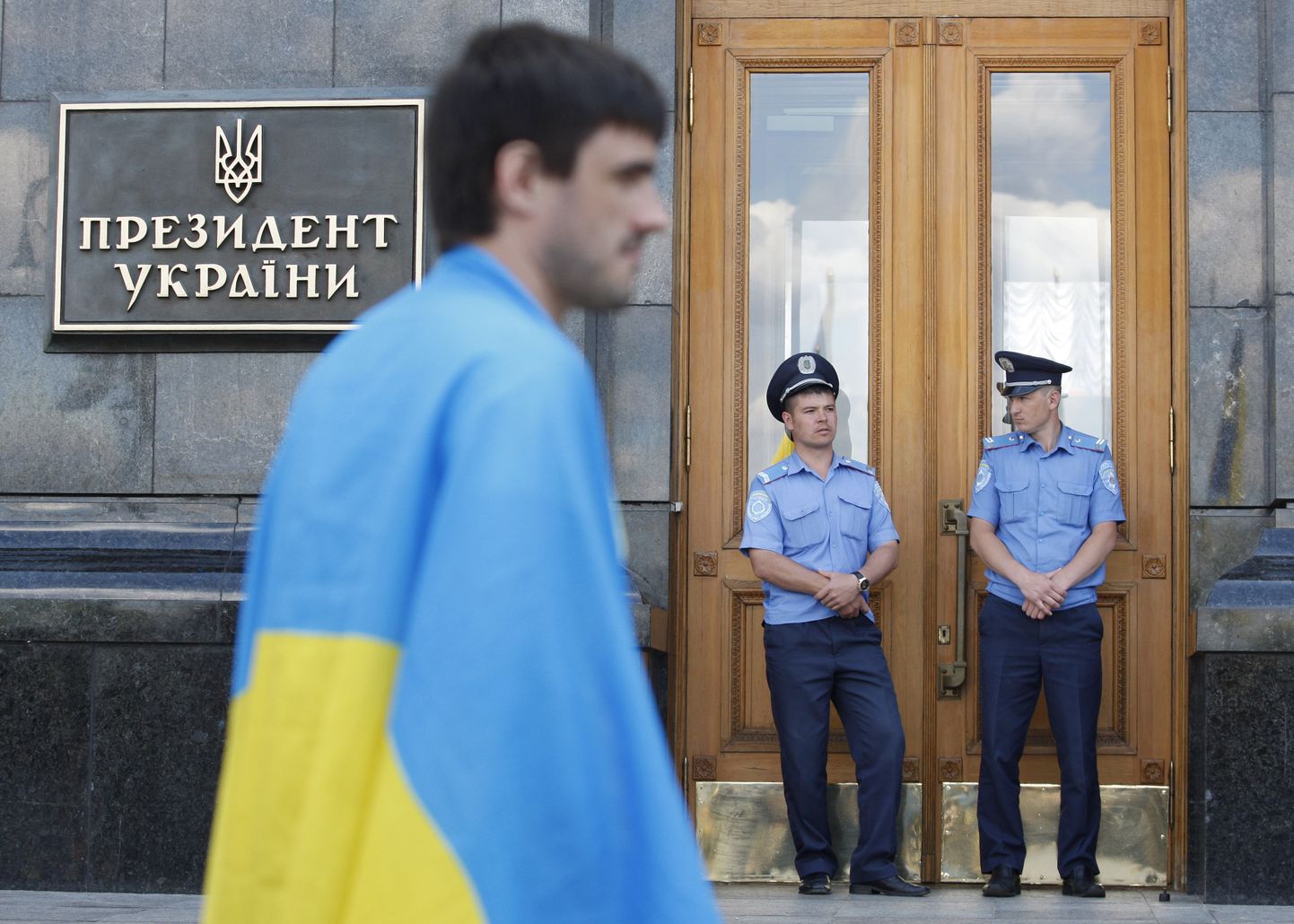 Ukraina lippu mähitud meeleavaldaja Ukraina valitsushoone ees.