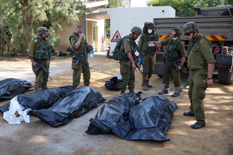 10 октября 2023 г., Кфар-Аза. Израильские солдаты стоят рядом с телами людей, убитых террористами ХАМАС. 