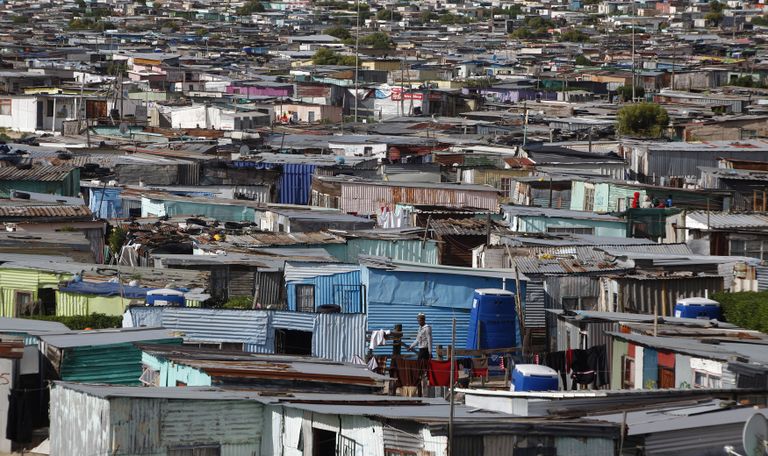 Residents walk through shacks in Cape Town's crime-ridden Khayelitsha township in this picture taken July 9, 2012. At least 11 people have died at the hands of vigilantes in the township since January as angry residents, tired of poor policing, take the law into their own hands. Picture taken July 9, 2012. To match Feature SAFRICA-CRIME/  REUTERS/Mike Hutchings (SOUTH AFRICA - Tags: CRIME LAW TPX IMAGES OF THE DAY)