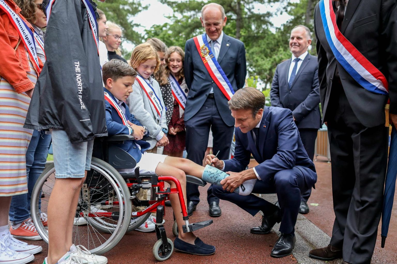 Prantsuse president Emmanuel Macron Põja-Prantsusmaal Le Touquet`s valimisjaoskonna ees ratastoolis poisi kipsile autogrammi andmas.