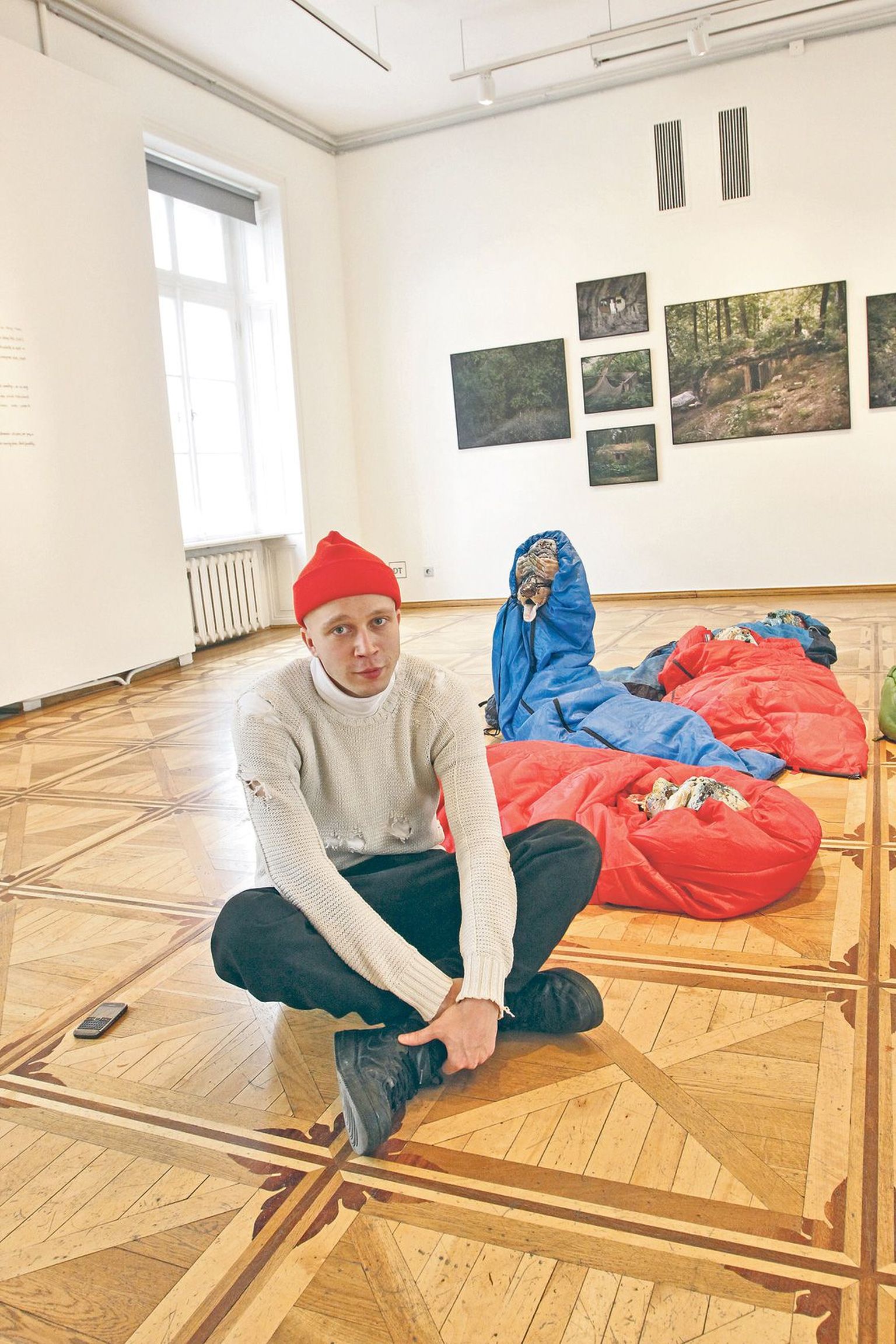 Näituse kuraator Sten Ojavee (26) on võtnud istet Kris Lemsalu 
installatsiooni «Fantoomide laager» (2012) juures. Seinal on 
moskvalase Danila Tkachenko fotoseeria «Põgenemine» (2014).