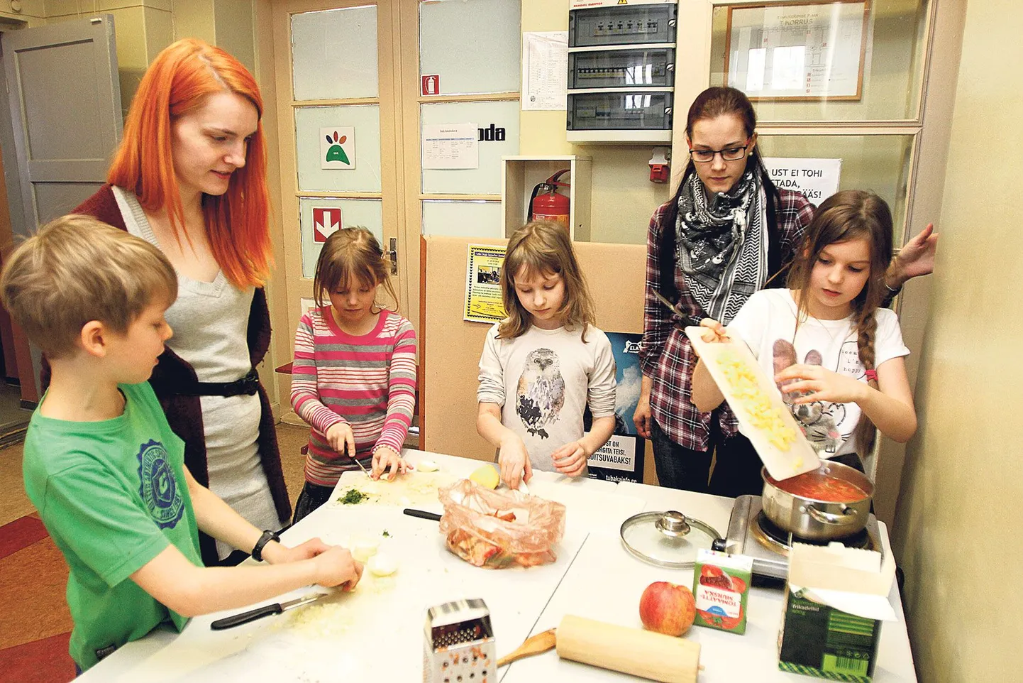 Jaan (vasakult) hakib sibulat, talle tuli appi Jenna. Teele lõigub veel viimaseid kartulikuubikuid ning Miariin paneb tükeldatud kartulid juba potti. Laudkonna juhendaja Merlin Tõnisson (paremal) jagab lastele nippe köögis toimetulekuks ning Lille maja linnalaagri üks korraldajaist Reelika Lodjak käib aeg-ajalt kontrollimas, kas kõik läheb plaani järgi.