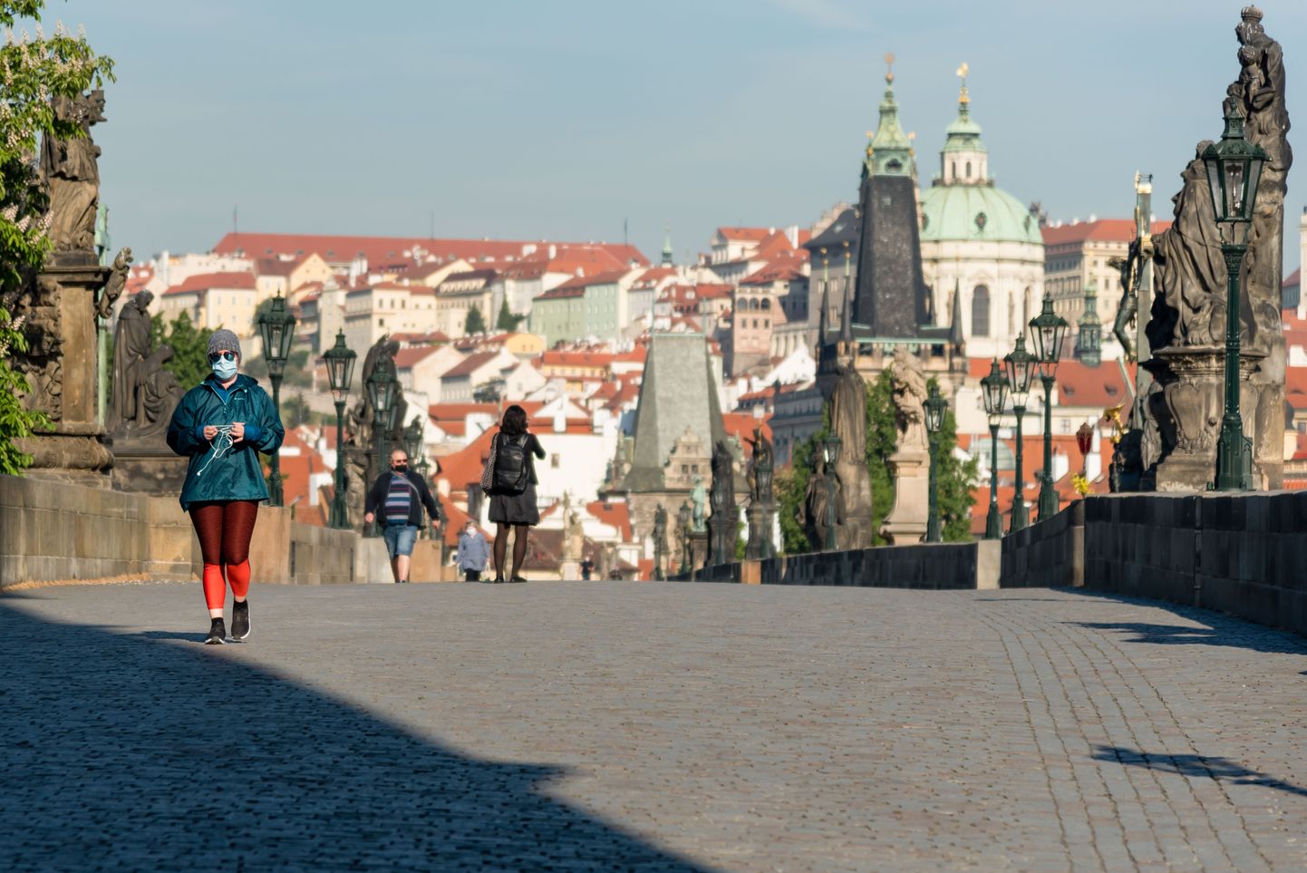 Kaitsemaskis naine jalutamas Prahas Karli sillal.