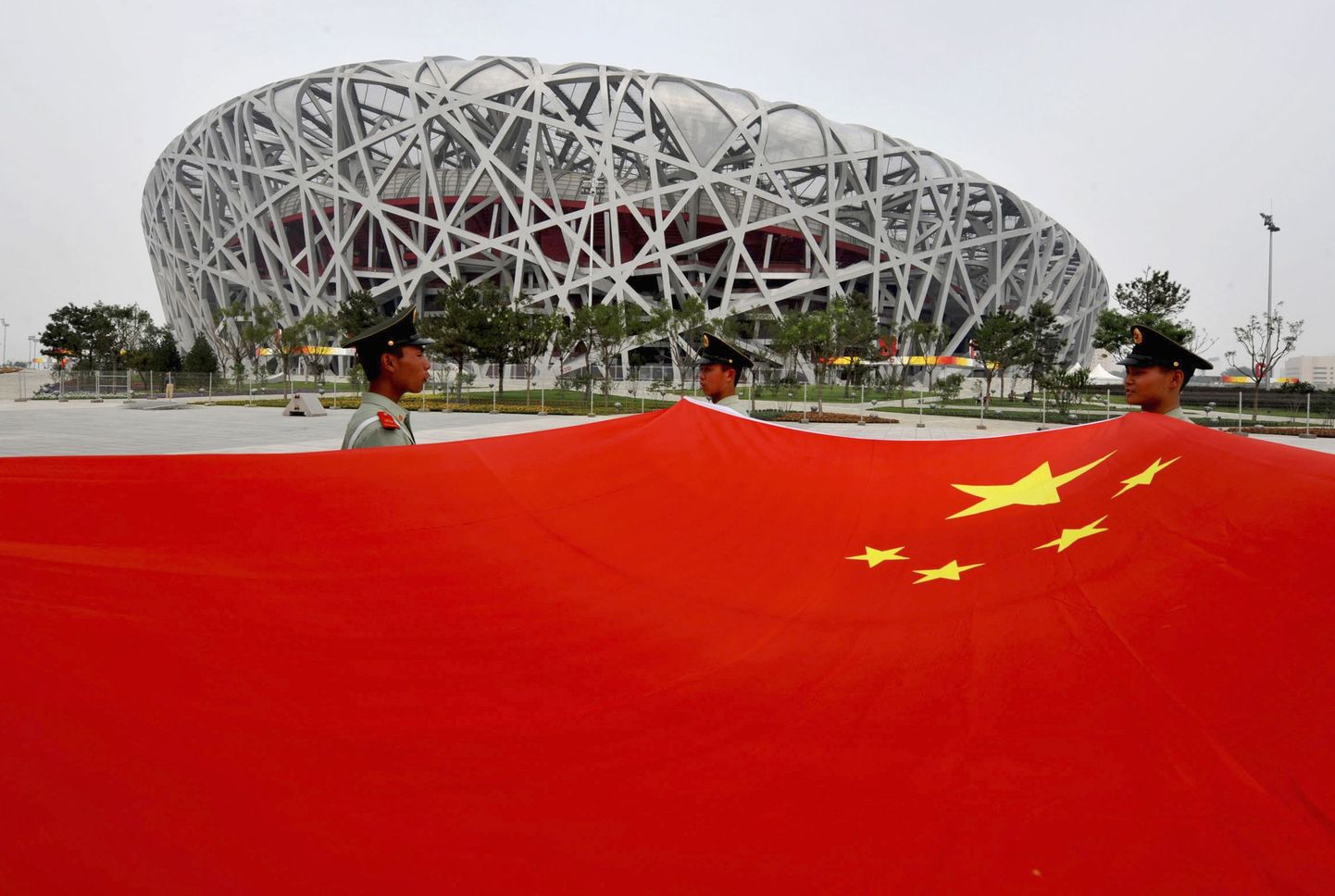 Hiina paramilitaarsed korravalvurid kandmas suurt punalippu Pekingi olümpiastaadioni ees.