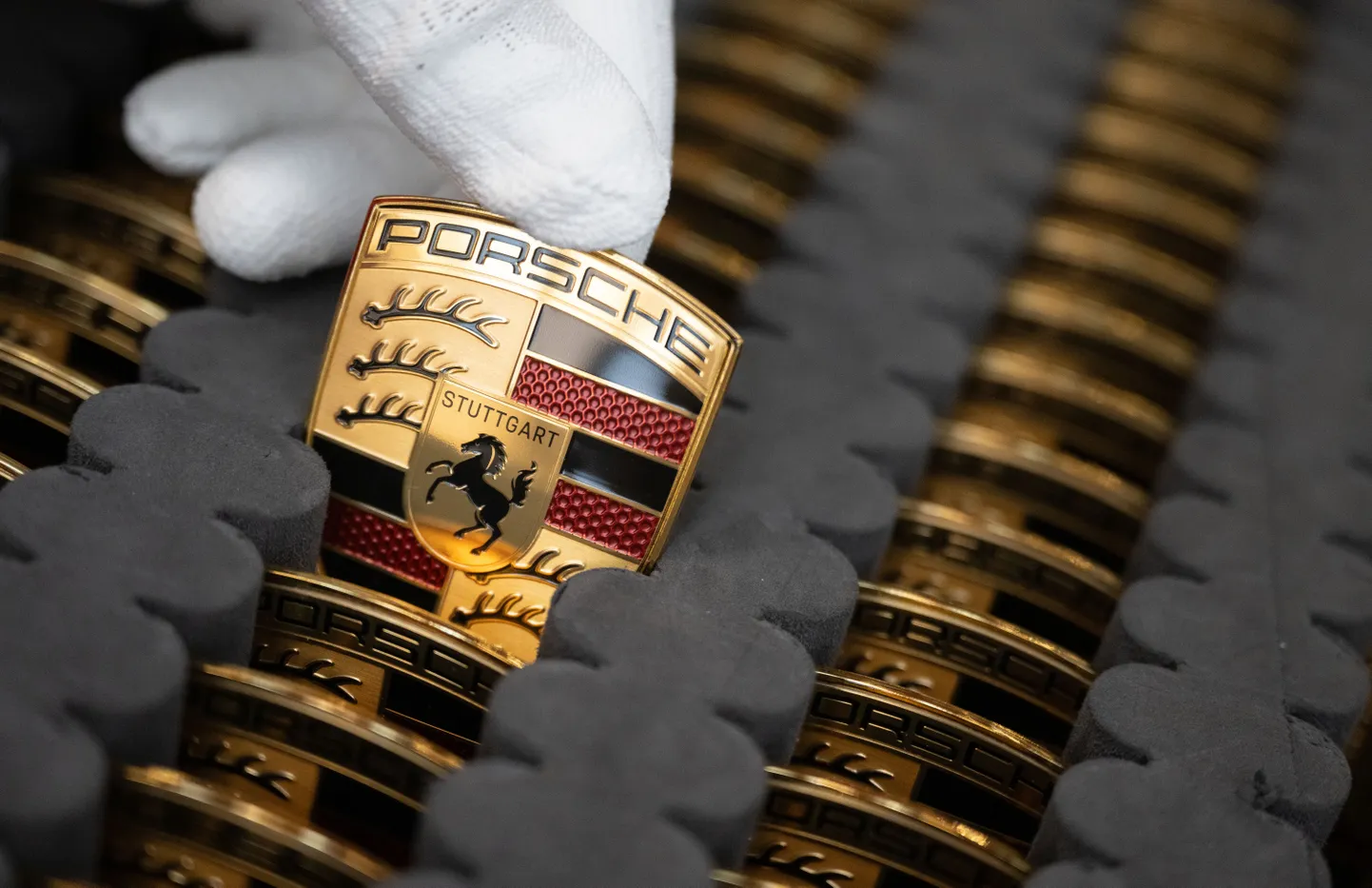 Baden-Württemberg, Stuttgart: Porsche AG töötaja Zuffenhauseni peatehases näitamas Porsche embleeme, mis kinnitatakse täiselektrilise Porsche Taycani kapottidele.