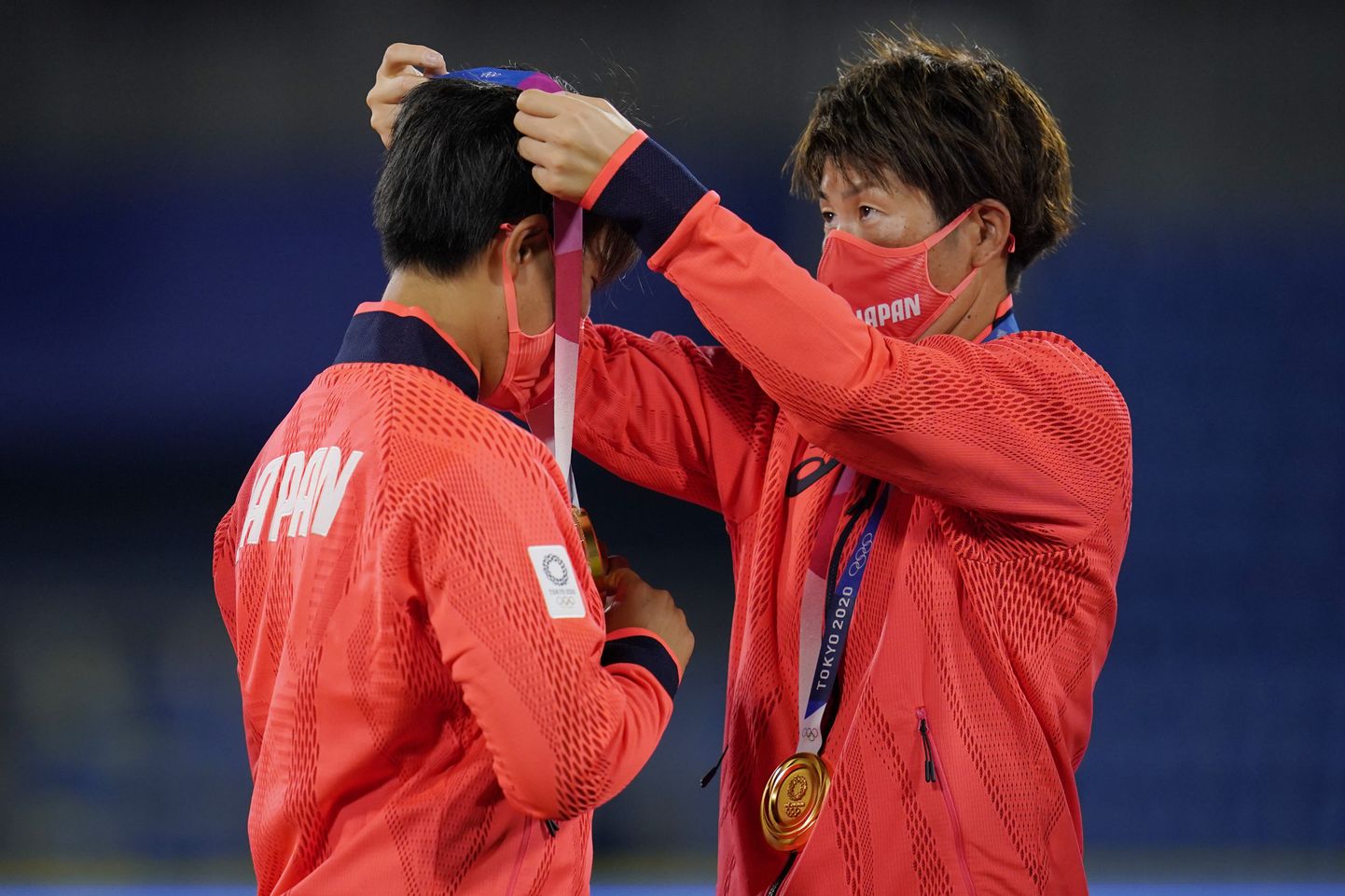 Japānas softbola izlases spēlētāji kar sev kaklā olimpiskās zelta medaļas.