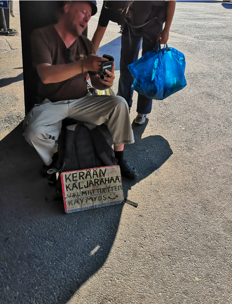 Перед круизным терминалом сидит мужчина и собирает денежные средства с помощью честной надписи на плакате: " Я собираю деньги на пиво".