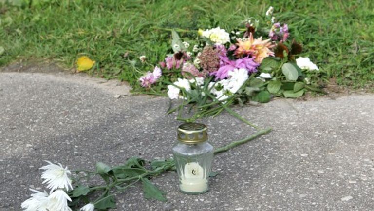Ziedi un svece uz taciņas, kas atrodas blakām vietai, kur tika atrasta noslepkavotā desmitgadīgā Diāna Kozlovska 