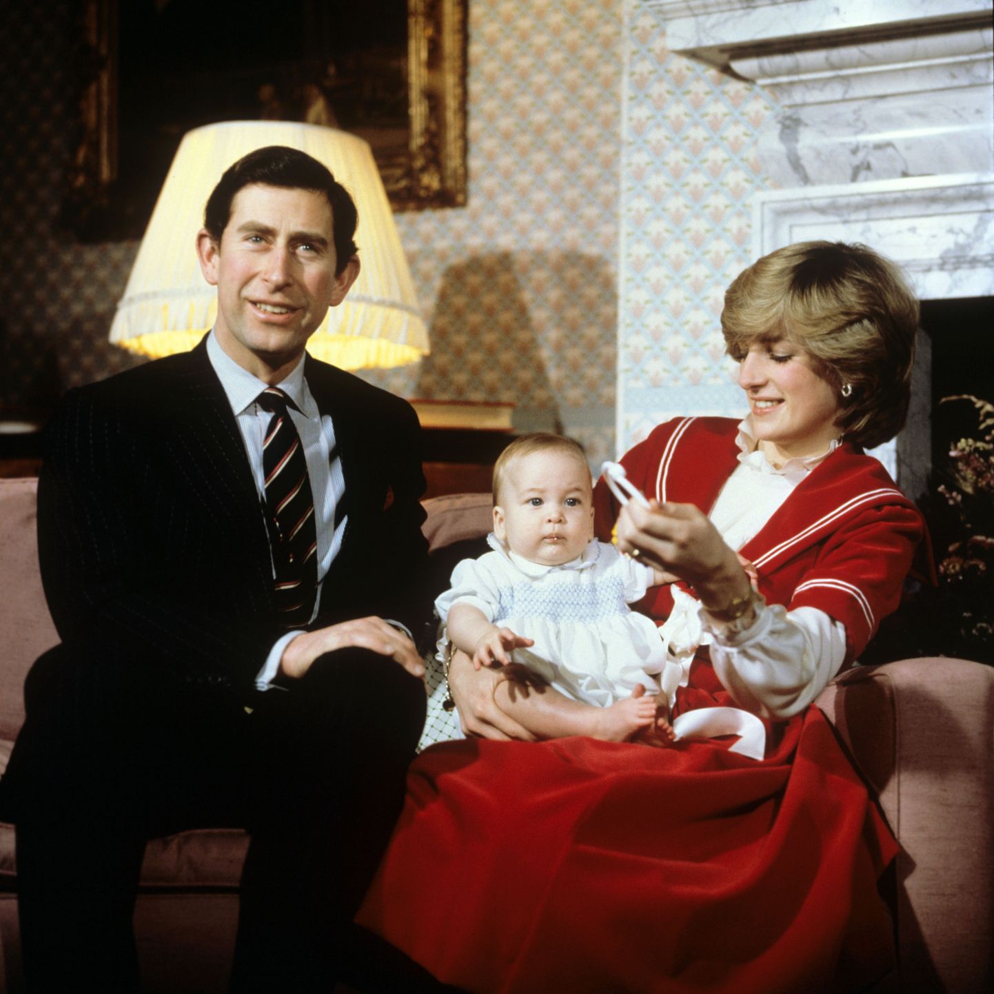 Prince Charles, Diana Princess of Wales and Prince William play with a rattle on the sofa at Kensington Palace London