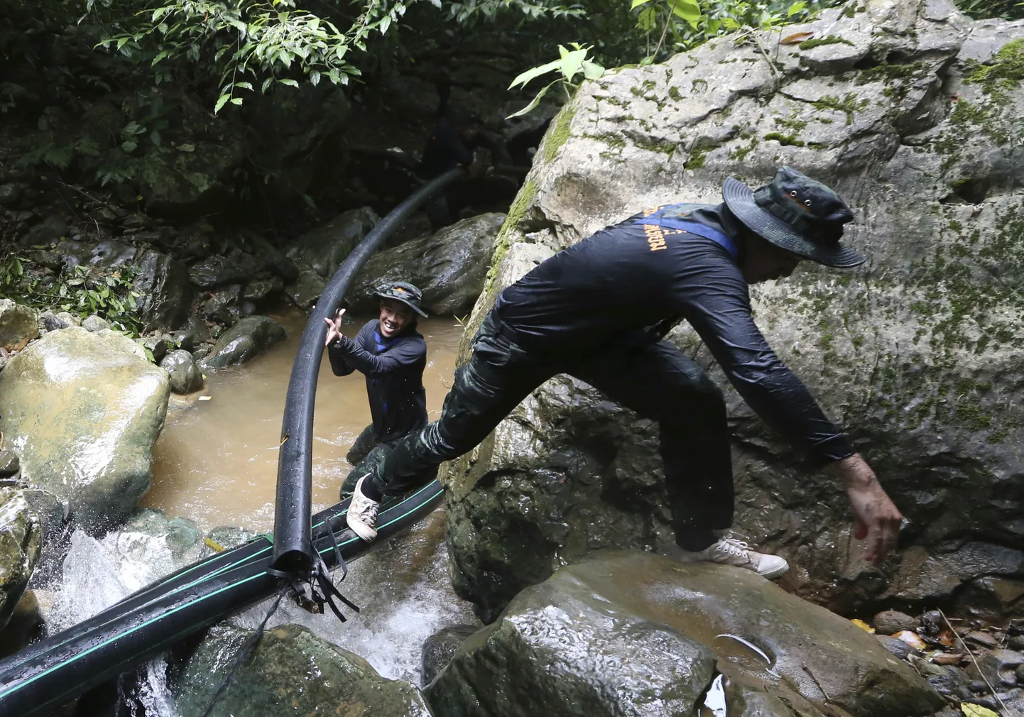 Sõdurid vedamas torusid, millega koopast vett välja pumbatakse.
