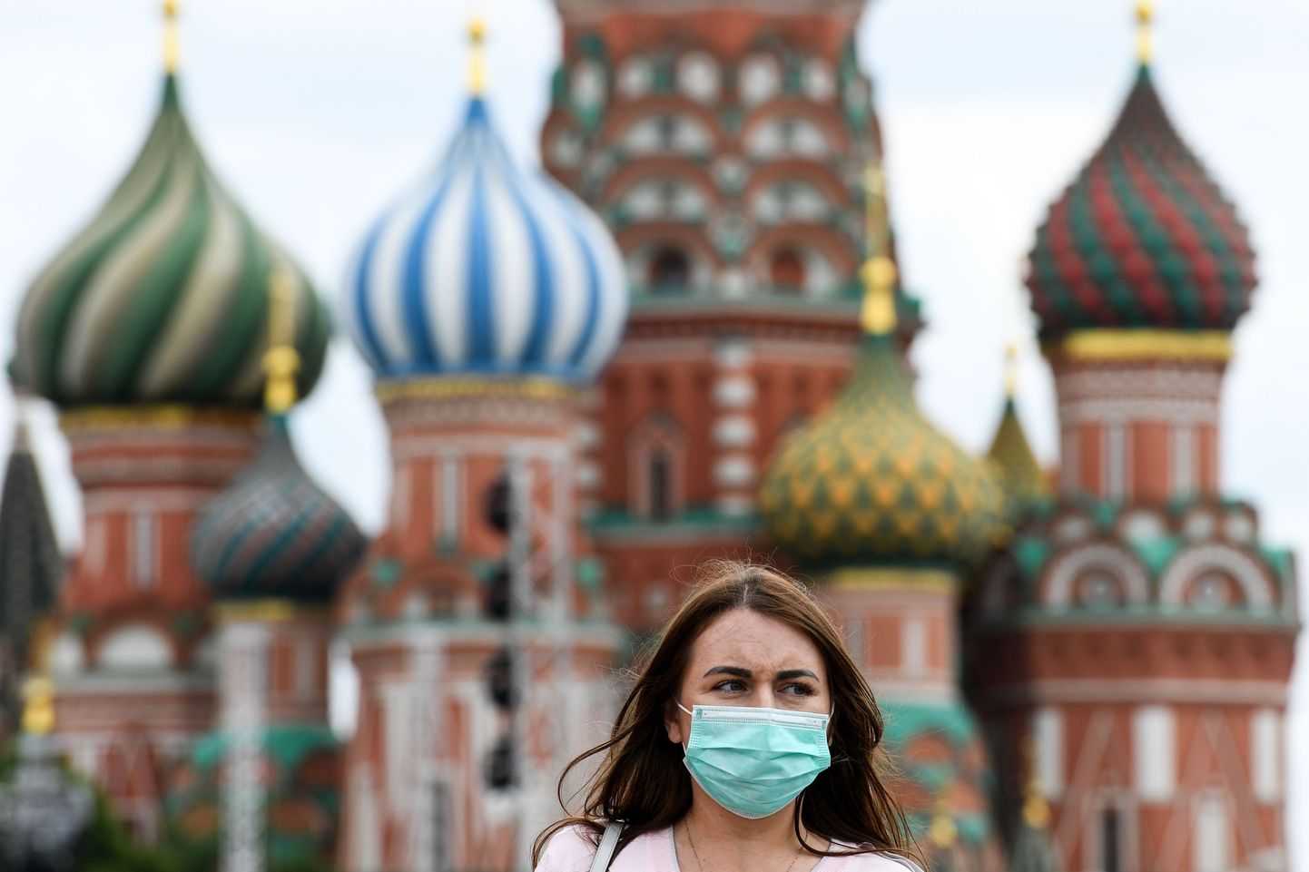 A woman wearing a protective face mask walks in front of the Saint Basil's Cathedral as part of the annual book fest on the Red Square in downtown Moscow on June 6, 2020, during the first public event since the country eased lockdown measures taken to curb the spread of the COVID-19 pandemic, caused by the novel coronavirus. (Photo by Kirill KUDRYAVTSEV / AFP)
