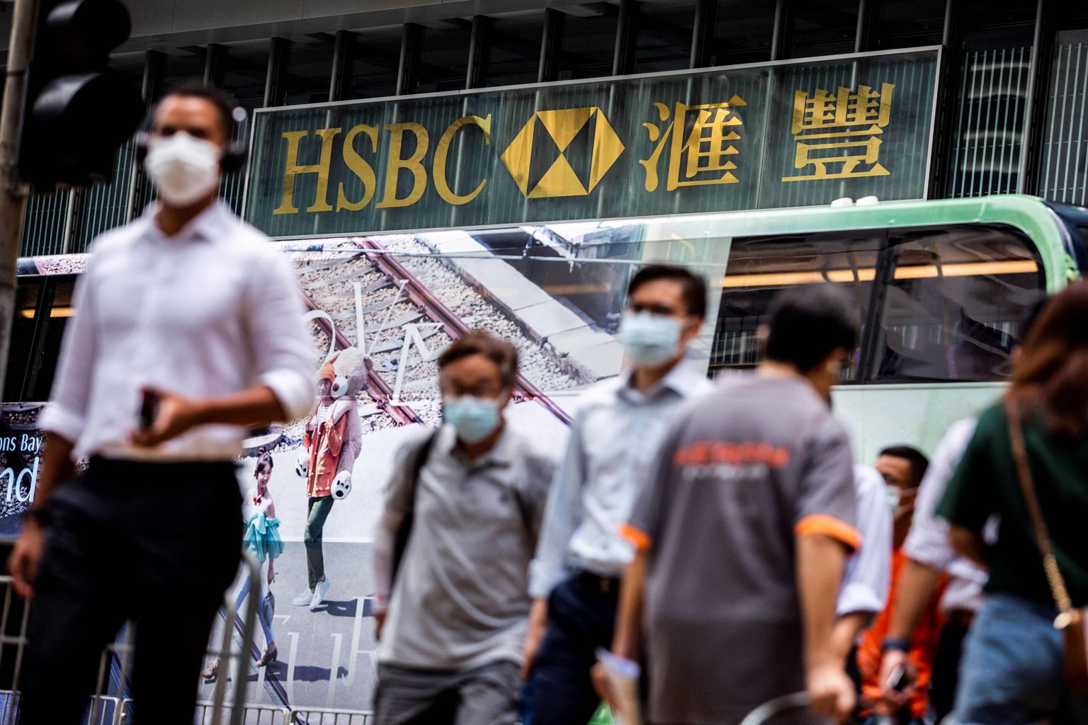 Jalakäijad ületamas teed HSBC Hongkongi peahoone ees.