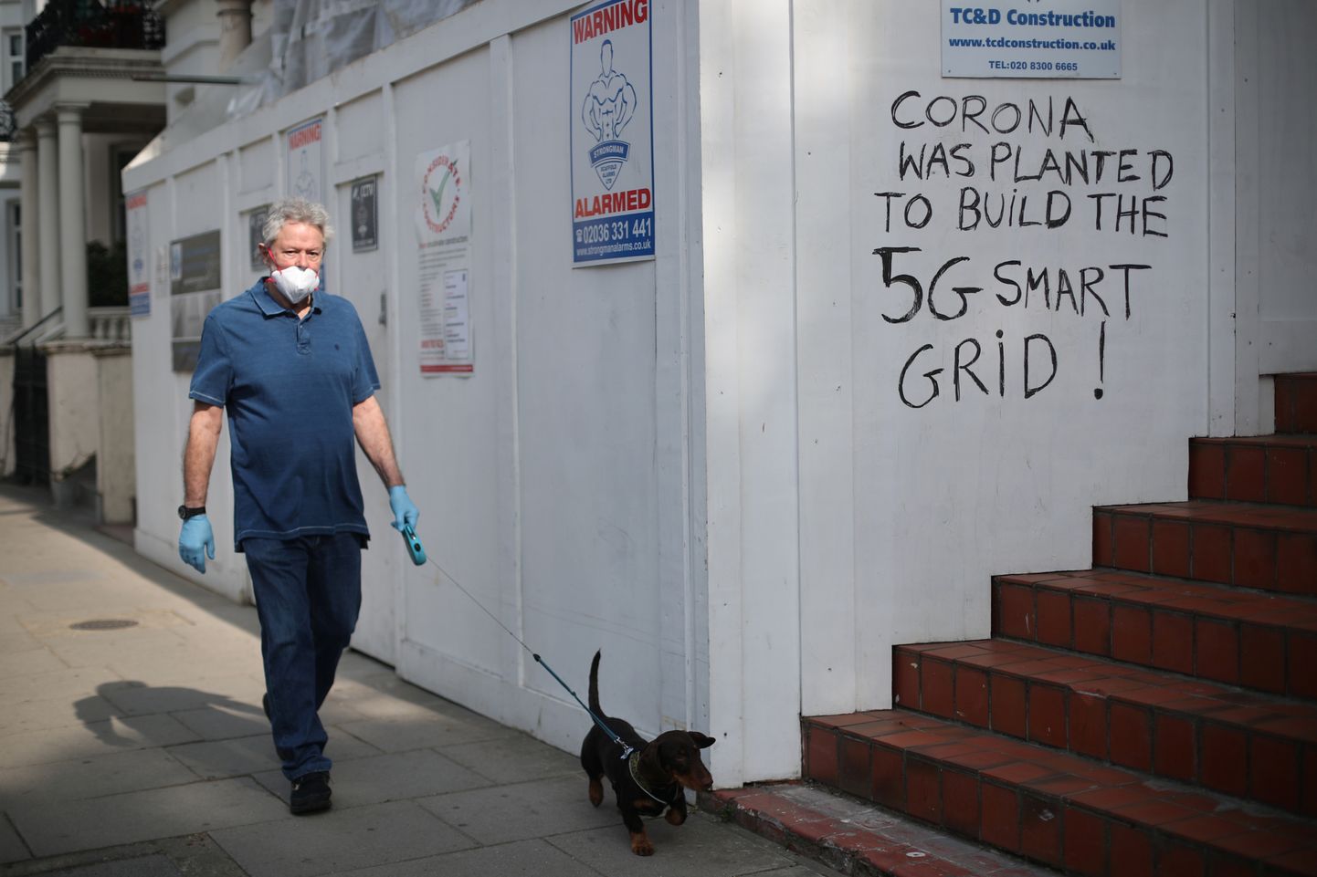 Kaitsemaskis mees möödumas Londonis seinale kritseldatud kirjast «Koroona tekitati selleks, et ehitada 5G-nutivõrku!».